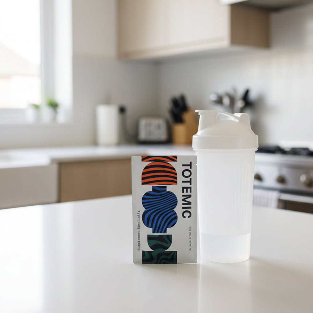 Clear shaker bottle with white cap on a clean kitchen counter, next to a TOTEMIC sachet.