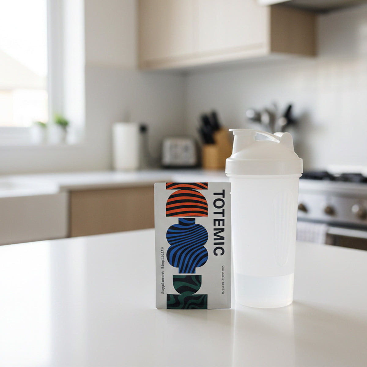 Clear shaker bottle with white cap on a clean kitchen counter, next to a TOTEMIC sachet.